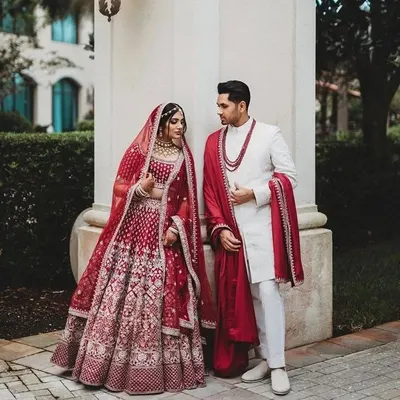 A classic red and white combination for a timeless wedding look. I designed the bride's intricate red lehenga to perfectly complement the groom's elegant white sherwani with a matching red shawl.
