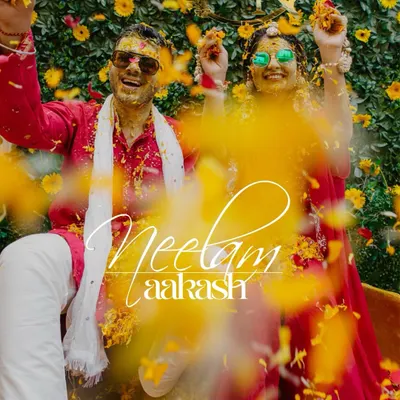 A fun and vibrant shot of the couple during their Haldi, showered with marigold petals.