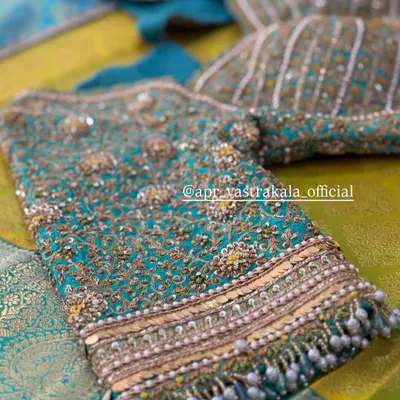 A stunning close-up of a teal bridal blouse, showcasing dense zardosi embroidery and cascading pearl beadwork for a truly opulent finish.
