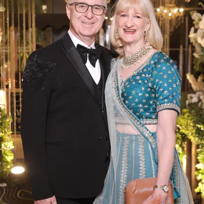 A classic and elegant look for wedding guests. This gentleman is wearing a timeless black tuxedo with a bow tie, perfectly complementing his partner's traditional attire.