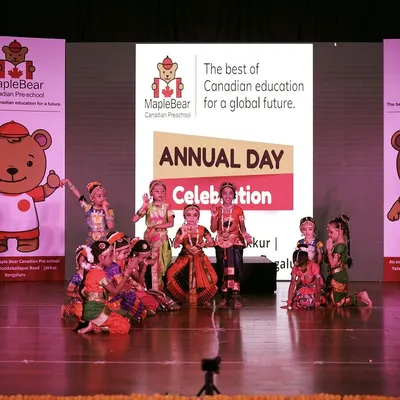 A vibrant group of young performers in traditional attire during the Maple Bear Canadian Preschool annual day. I ensure the stage is perfectly set with branded standees and professional lighting to spotlight the students.