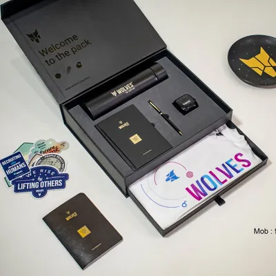 A high-quality, aspirational shot of a complete, well-designed welcome kit for "Wolves". It shows a t-shirt, bottle, diary, pen, and more in a premium box, showcasing our capability in creating bespoke onboarding experiences.