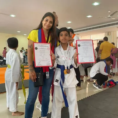 Posing with one of my students who proudly displays his certificates and medal after a championship. Seeing their hard work pay off is one of the most rewarding parts of being a coach.
