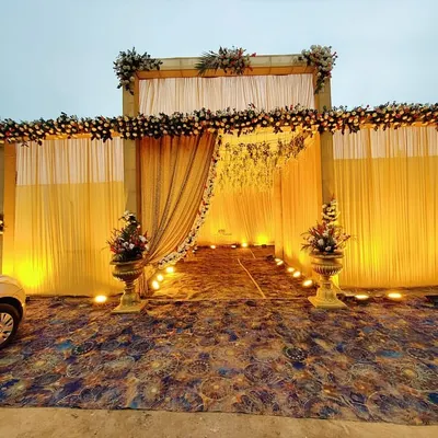 This is the kind of grand entrance I create for large wedding functions. The structure is decorated with pastel floral arrangements and elegant drapes, with warm uplighting to create a welcoming passage for guests arriving in the evening.