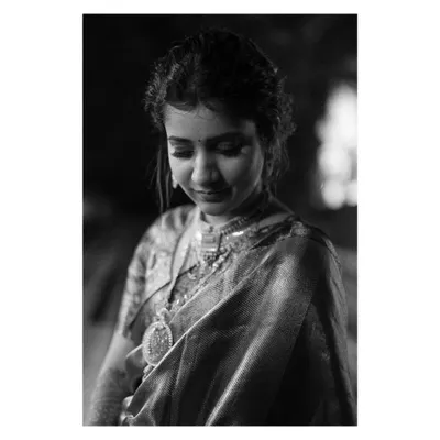 A timeless black and white portrait of the bride. Her downward glance and the soft lighting highlight the intricate details of her jewelry and the quiet grace she exudes.