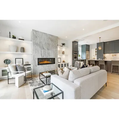 This open-plan living area features a striking marble-clad fireplace as its focal point. The space flows into a modern kitchen, demonstrating how we use materials and layout to connect different functional zones into one harmonious design.