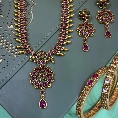 This is a beautiful temple jewellery necklace set with matching earrings and bangles. The rich ruby and green stones give it a classic look, perfect for wearing with silk sarees for a wedding or festival.