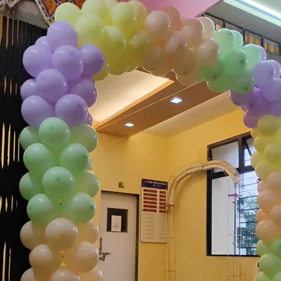 A soft and welcoming entrance for any daytime event. This balloon arch uses a beautiful pastel rainbow palette of purple, green, yellow, and peach, creating a cheerful and inviting entryway.
