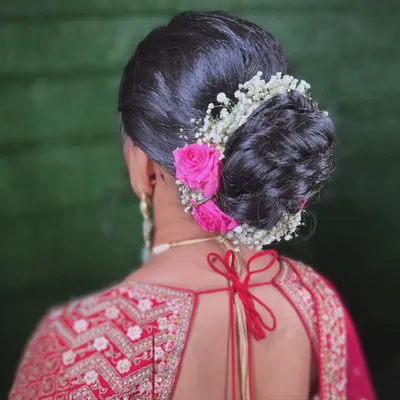 A classic bridal bun, elevated with a mix of baby's breath and delicate pink roses. This hairstyle is perfect for securing a dupatta while adding a touch of romance.