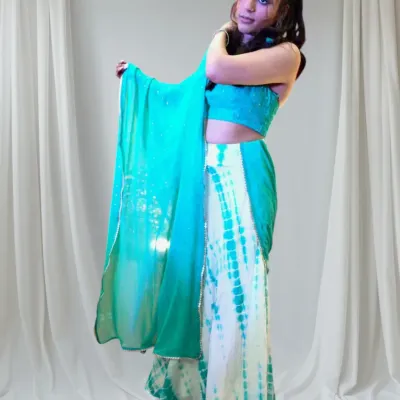 This custom Sangeet outfit features a modern tie-dye skirt and a sparkling halter blouse. The design allows for easy movement while creating a stylish and memorable look.