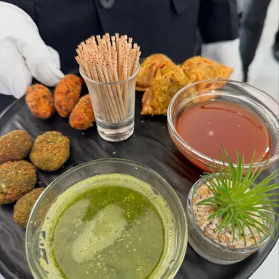 A platter of our classic Indian fried appetizers, served by our white-gloved staff. This selection includes assorted veg cutlets and samosas, paired with traditional green chutney and sweet tamarind chutney.
