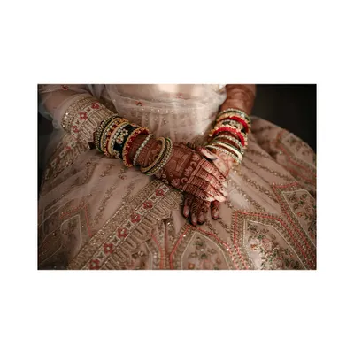 A close-up on the bride's hands, showcasing her intricate bangles and mehendi, a beautiful detail of her bridal attire.