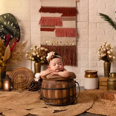 A perfect pose. This baby is resting their arms on the edge of a rustic wooden bucket, creating an incredibly sweet and relaxed portrait within our earthy boho setup.