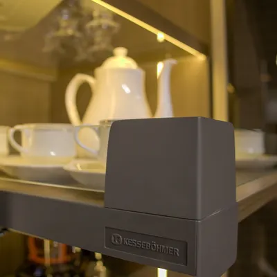 A close-up on quality hardware from Kesseböhmer, a leader in furniture fittings. This detail shot of a hinge on a glass shelf highlights our commitment to using durable, high-performance components to ensure your furniture lasts a lifetime.
