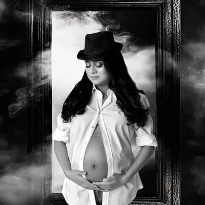 A powerful and artistic maternity portrait. This editorial style uses dramatic lighting, props, and a monochrome finish to create a striking image that celebrates the mother's strength.