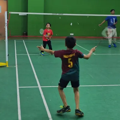 A young player gets ready to return a shot during a doubles game. Introducing match play early helps kids understand court positioning and strategy in a real-game scenario.