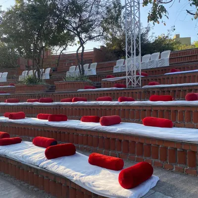 For a Ram Kalash function at an amphitheater, I arranged comfortable floor seating for guests. White sheets are laid out on the steps with red bolsters, ensuring a clean and organized setup for the event.