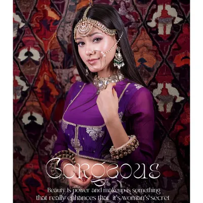 A gorgeous portrait from a bridal look photoshoot. The model's regal purple outfit and intricate jewelry are captured against a rich, patterned backdrop, creating a royal and elegant image.