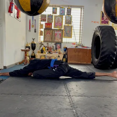 A full pancake stretch, a deep stretch for the hips and hamstrings. This level of flexibility is crucial for high kicks and injury prevention.