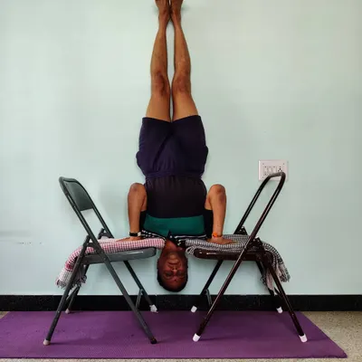 Chair Shirshasana (Headstand). Using two chairs creates a stable platform for the shoulders, removing pressure from the neck. This makes the king of asanas safer and allows you to focus on the alignment of the spine and legs.