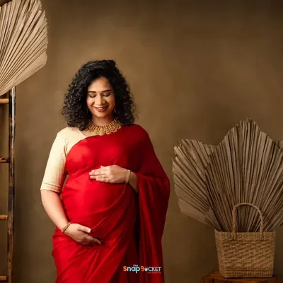 The elegance of a saree for a maternity shoot is just unmatched. This mom-to-be looks absolutely radiant in a vibrant red saree, cradling her bump in my boho-themed studio.