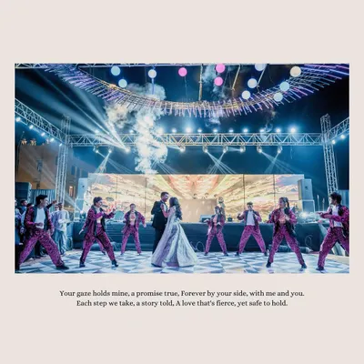 A grand performance on the Sangeet stage. The couple is surrounded by dancers, smoke, and lights, creating a spectacular moment that feels like a scene from a movie.
