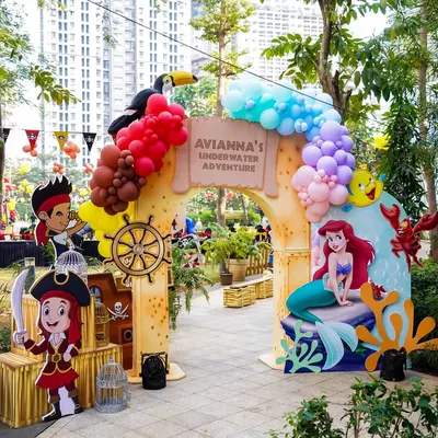 A spectacular outdoor entrance for a 'Mermaids vs. Pirates' party, perfectly blending the two themes with character cutouts and balloon arches.