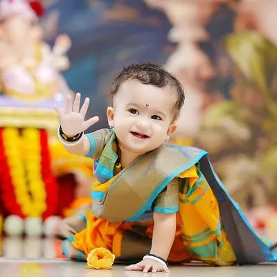 A joyful baby waves at the camera during our 'Bappa Morya' photoshoot. Dressed in a traditional saree-style dhoti, he is the perfect little devotee for Ganesh Chaturthi.