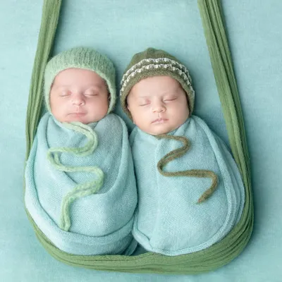 Born together, best friends forever. This hanging sling pose is perfect for showcasing newborn twins, keeping them snug and close just like they were in the womb.