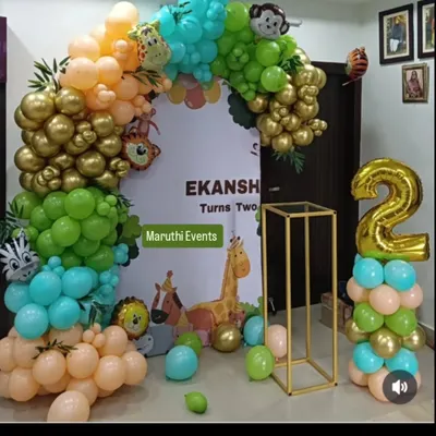 A beautiful jungle-themed party with modern, retro-colored balloons. The organic arch in shades of green, gold, and peach is paired with a cute animal backdrop and a gold stand.