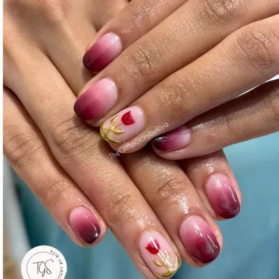 A beautiful ombré set with a touch of hand-painted artistry. The nails feature a deep red to pink fade, with a delicate tulip painted in gold on the accent nail.