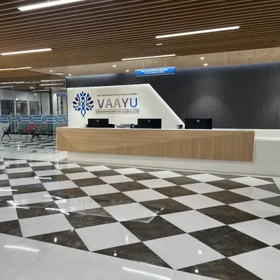 The main reception desk at Venkateshwar Hospital's cancer block. The design uses a clean, modern aesthetic with wood accents and a polished checkerboard floor to create a welcoming and professional first impression.