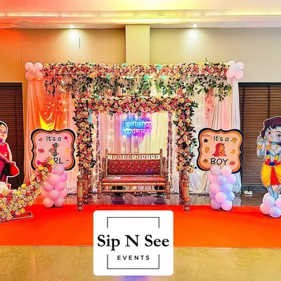 A complete stage setup for a baby shower at Lodha Amara's clubhouse. This decoration includes a floral jhula, a 'Kunitari yenar ga' neon sign, gender reveal props, and a floral moon seat, covering all the essentials for a grand celebration.