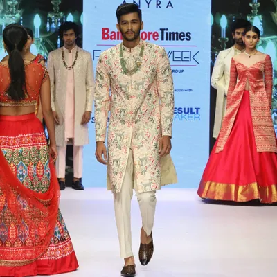 A model walks the runway at Bangalore Times Fashion Week in one of my creations. This light pink sherwani is fully embroidered with a multi-color pattern, showcasing my commitment to detailed, artistic craftsmanship.