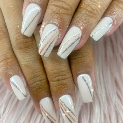A perfect example of sophisticated elegance. This design features a creamy white base on long, coffin-shaped nails, adorned with delicate, sparkling stripes in silver and rose gold.