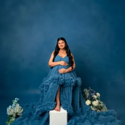 A solo portrait showcasing the grandeur of our blue ruffled tulle gown. The cascading fabric creates a stunning visual, perfect for a regal and memorable maternity photo.