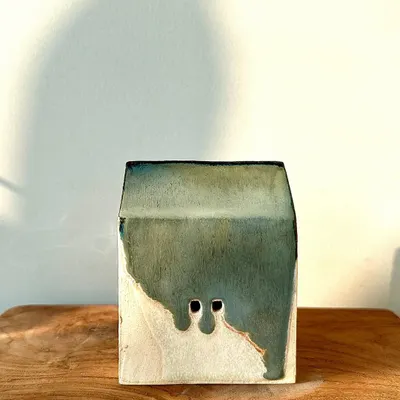 A miniature ceramic house with a beautiful green and white glaze. These small sculptures are a playful exploration of form and color.