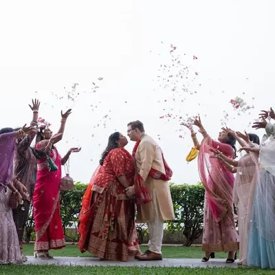 A beautiful moment from a multicultural wedding in Mumbai, where guests from different backgrounds shower the couple with flower petals.