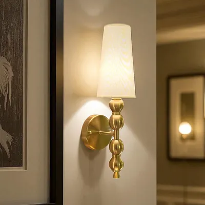 The Luminique Spire Wall Light is a classic choice for adding a focused glow. Its beaded column and simple tapered shade make it ideal for placing on either side of a bed, a mirror, or a piece of art.