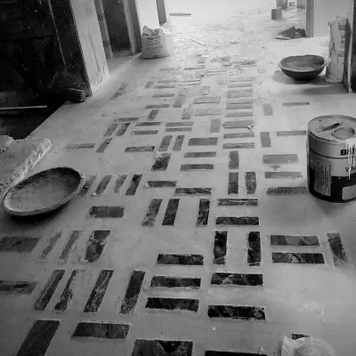 A modern geometric pattern being laid on the floor of a project in Delhi. We used pieces of dark stone set into the concrete to create this custom design.