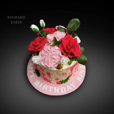 A vibrant bouquet of handmade sugar flowers sits atop this beautiful birthday cake. I used various shades of pink and red to create a lush, realistic floral arrangement.