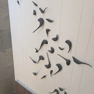 A close-up of the custom 3D bird sculpture from the 'Casa Vitals' project. Each bird is crafted and placed to create a sense of dynamic movement on the wall.