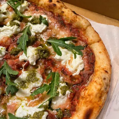 A beautiful close-up of my Pesto Burrata pizza. The combination of creamy burrata cheese, fresh pesto, and peppery arugula on our signature crust is simply divine.