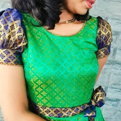 Here is a close-up of the 'Neelam' dress, custom-made from a client's saree. You can see the beautiful detail of the green and gold brocade fabric, the contrasting blue puff sleeves, and the delicate beadwork along the neckline.