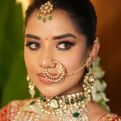 A close-up of the quintessential Indian bride. The sleek center-parted bun provides a perfect base for the maang tikka and nath, creating a clean, royal profile for the wedding ceremony.