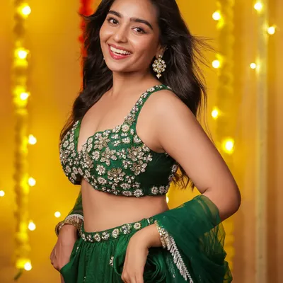 A joyful portrait of a model in a green embroidered lehenga, smiling brightly against a festive background of yellow lights. This shot captures the happy spirit of Diwali.