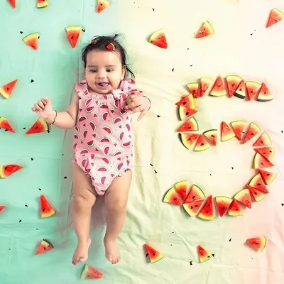 An adorable overhead shot from a baby milestone session, where a five-month-old is surrounded by watermelon slices arranged to form the number five. This highlights my creative and fun approach to baby photography.