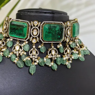 A stunning Victorian choker adorned with large emerald-colored stones and delicate strawberry beads. This is a statement piece that exudes luxury and is perfect for a grand reception.