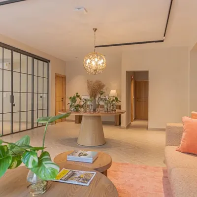The waiting lounge of this office is designed to feel calm and welcoming. We used a soft, earthy color palette with pops of coral, natural wood furniture, and plenty of indoor plants. A crittall glass partition separates the lounge from a meeting room, maintaining an open and airy feel while providing acoustic privacy.