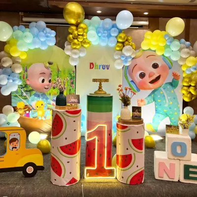 A grand Cocomelon themed first birthday for Dhruv. This elaborate setup includes multiple character cutouts, a Cocomelon bus, watermelon-themed pedestals, and a large, colorful balloon backdrop for an immersive experience.